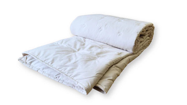 Cream-colored Crescent Moon alpaca and wool comforter spread out on a bed, showcasing its soft, cozy texture and plush design.