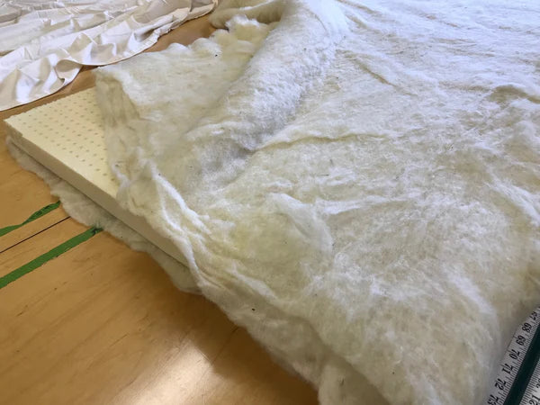 Holy Lamb Organics wool and latex mattress topper showing soft, plush fabric and neatly stitched edges for added comfort.