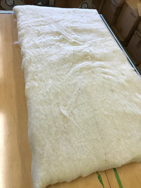 Holy Lamb Organics wool and latex mattress topper laid on a bed, showcasing its plush, natural materials and comfortable design