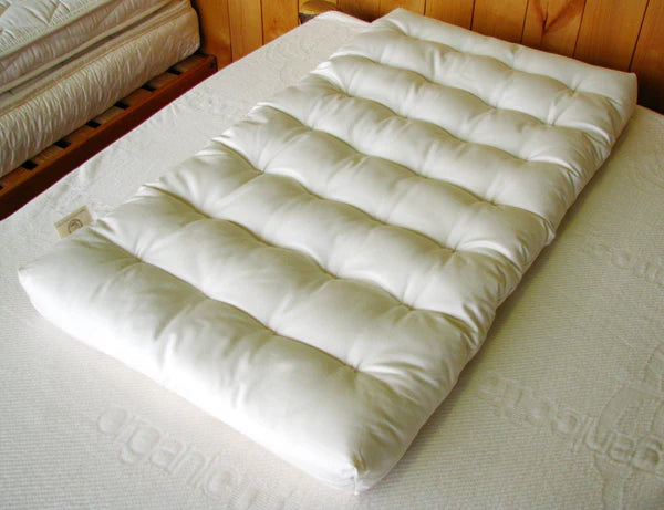 Natural wool bassinet mattress for babies by Holy Lamb Organics, showing the soft, breathable fabric surface and plush interior.