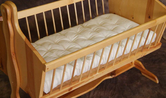 Natural wool bassinet mattress for baby by Holy Lamb Organics, showing soft, breathable wool fill and secure fitted cover.