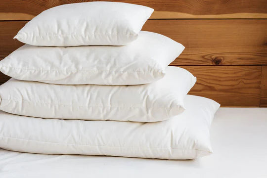 Holy Lamb Organics wool-filled bed pillows stacked on a bed with soft linens and natural bedding for comfortable sleep.
