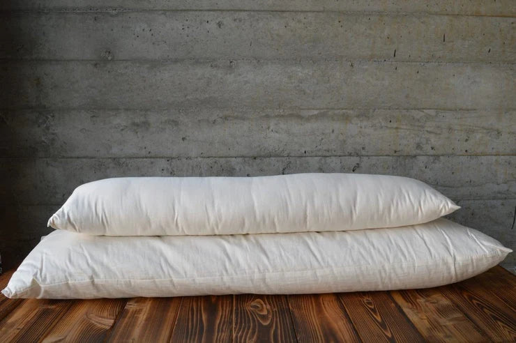 Holy Lamb Organics natural body pillow lying on a bed, showcasing its soft, plush fabric and ergonomic shape for restful sleep.