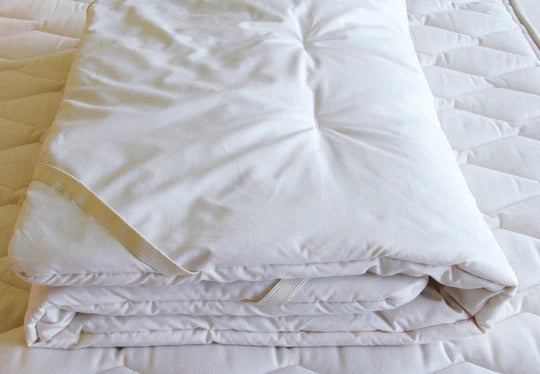 Folded Holy Lamb Organics certified organic crib mattress topper for baby, showing soft, natural fabric and plush texture.