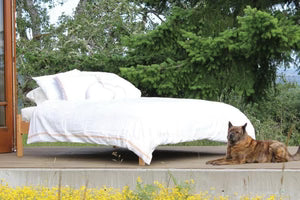 Organic cotton and wool futon by Soaring Heart, shown folded with natural beige fabric and plush filling for comfortable sleeping.
