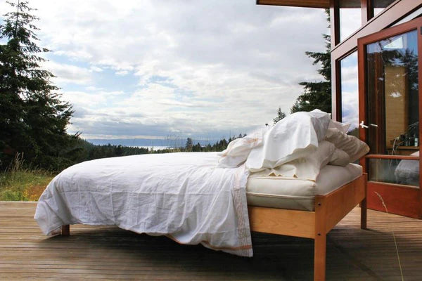 Organic cotton and wool futon mattress from Soaring Heart, showing a neatly folded, natural-fiber futon on a wooden bed frame.