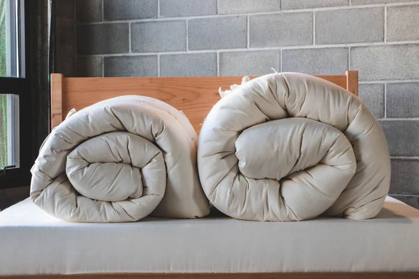Rolled Holy Lamb Organics quilted mattress topper with natural, plush quilting for added comfort and support.