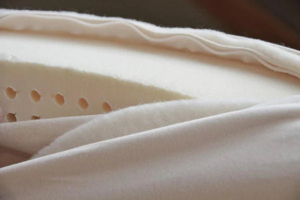 Organic latex shikibuton mattress by Soaring Heart, showing a neatly folded traditional Japanese bedding on a wooden floor.