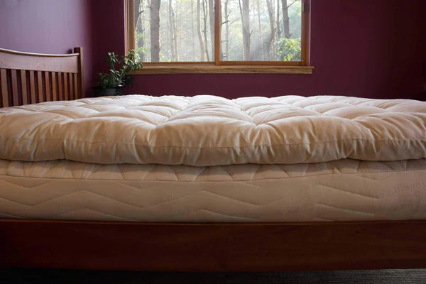 Organic quilted mattress topper by Holy Lamb Organics, plush and padded for added comfort on bed.