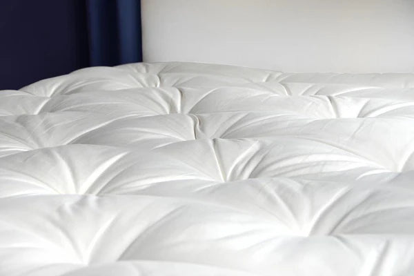 Organic wool mattress topper by Soaring Heart, plush, thick, and cozy for added comfort on a bed.