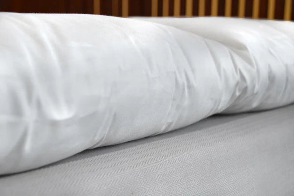 Organic wool mattress topper by Soaring Heart featuring plush, natural wool filling on a neatly made bed.