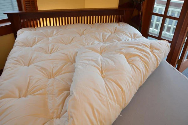 Organic Wool Mattress Topper by Soaring Heart, soft and plush, with natural wool filling and a fitted fabric cover.